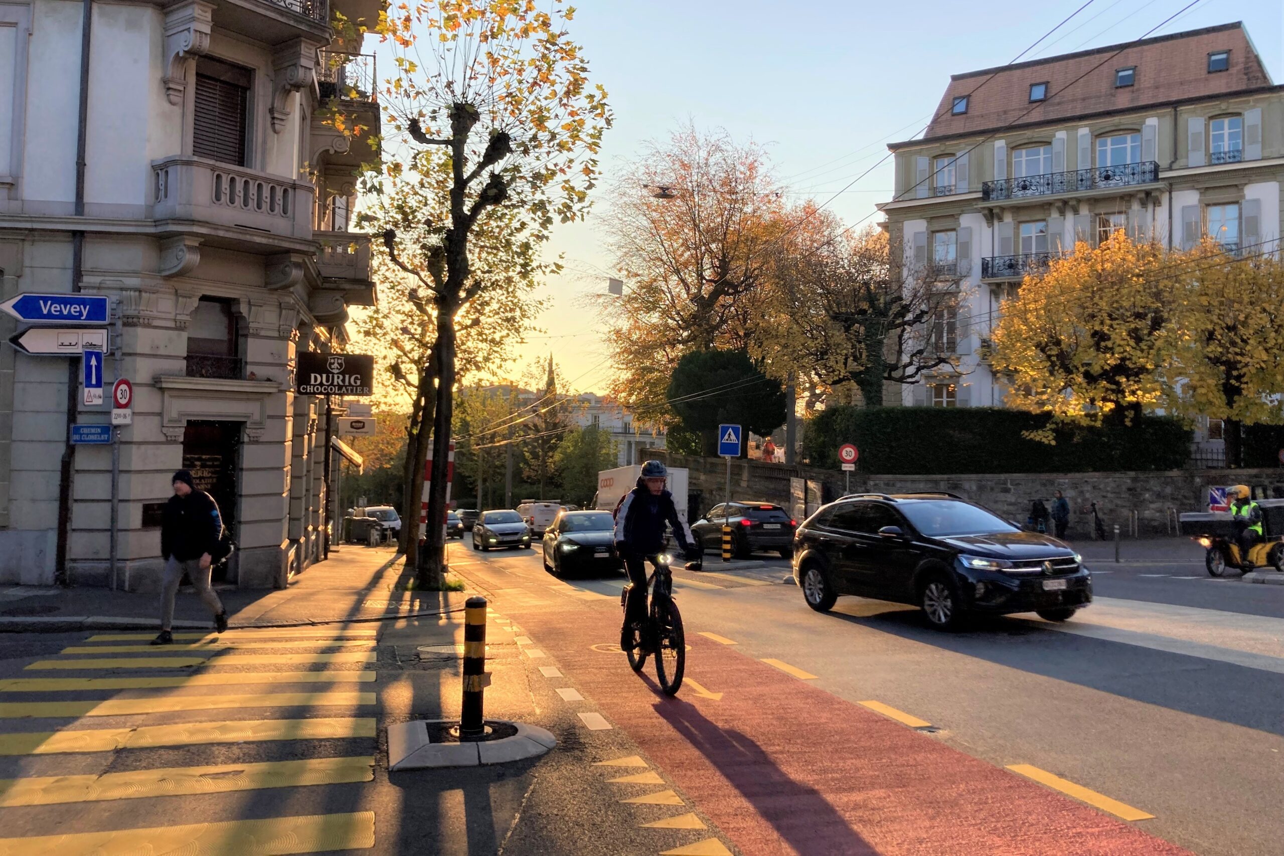 Eine Person fährt mit dem Velo auf einem rot eingefärbten Velostreifen auf einer Strasse mit viel Autoverkehr.